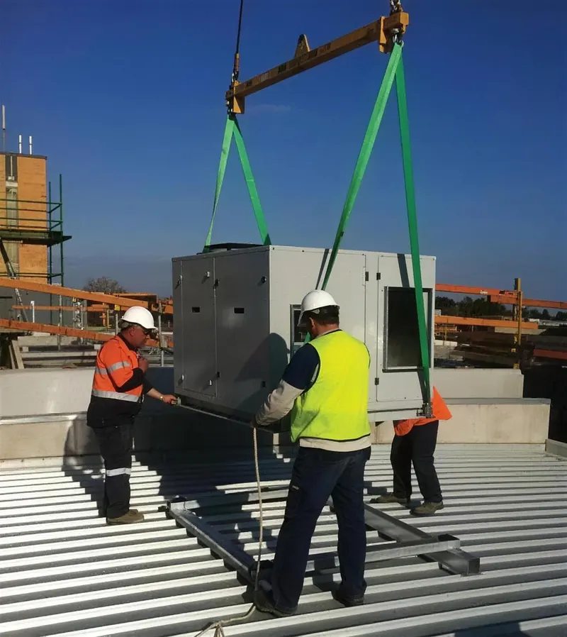 The team guiding a commercial unit onto a rooftop by crane