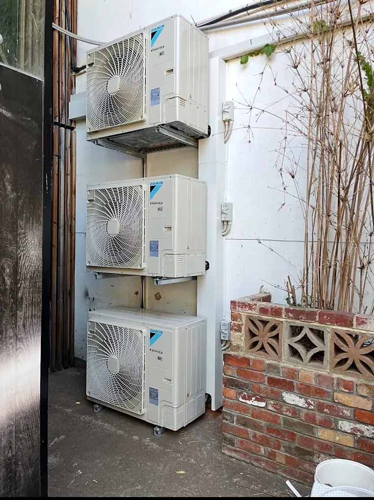 Three outdoor units stacked in a tight laneway